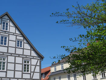 Low angle view of trees and building against blue sky