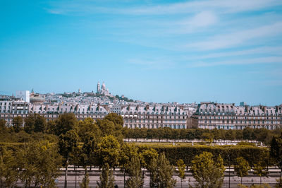 View of trees and buildings against blue sky