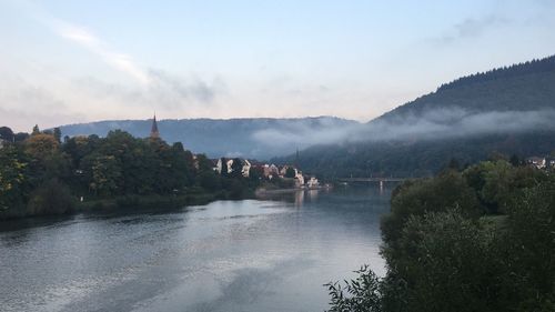 Scenic view of river by buildings against sky