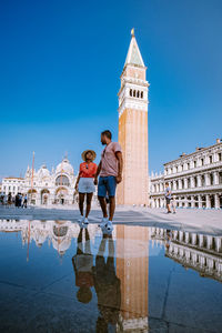 Reflection of people on building against clear blue sky