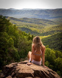 Rear view of woman sitting on mountain