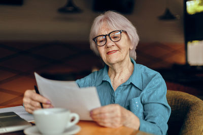 Senior woman looking at document at cafe