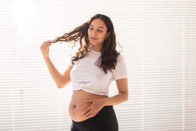 Portrait of beautiful young woman standing against wall