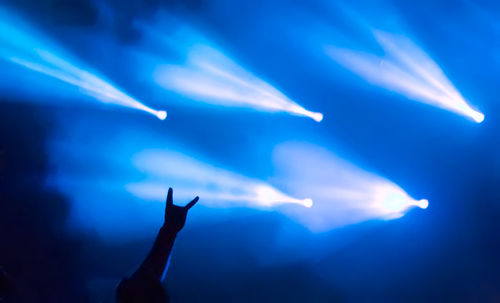 Low angle view of silhouette hand against blue sky at night