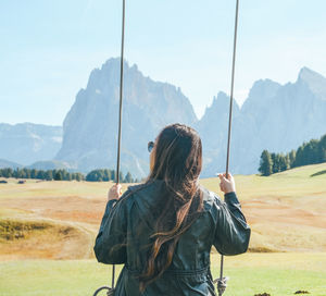 Rear view of woman standing on field against mountains