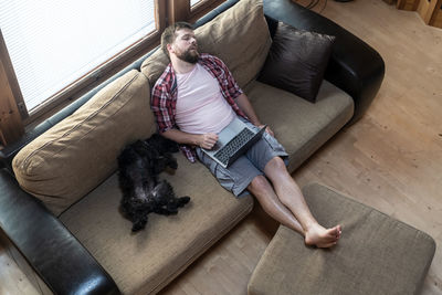 Midsection of woman with dog on sofa