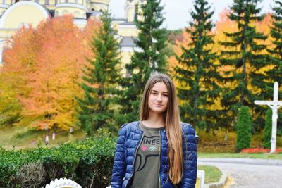 Young woman standing against trees at park