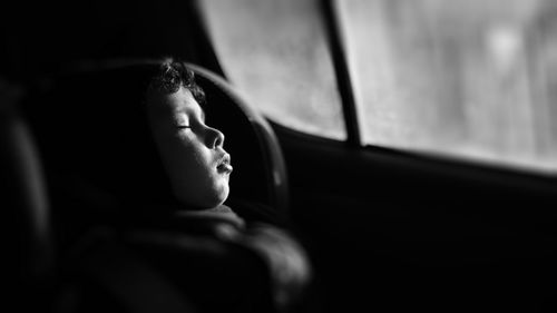 Close-up portrait of little boy sleeping in car