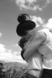 Side view of woman with arms raised against sky