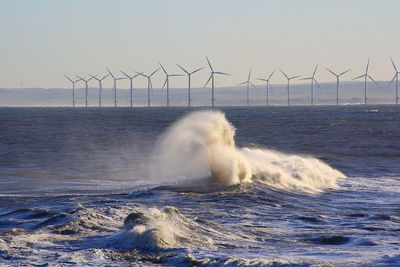 View of windmills on sea against sky