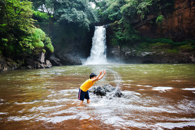 Boy surfing on rock in waterfall