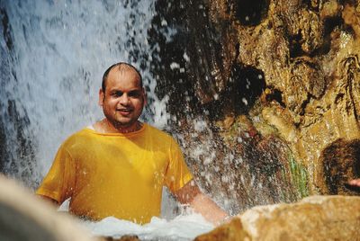 Portrait of man standing against waterfall