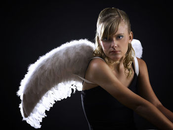 Portrait of young woman against black background