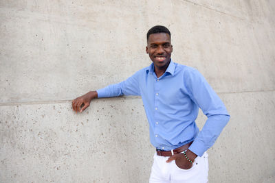 Portrait of young man standing against wall