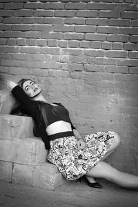 Portrait of woman sitting on brick wall