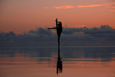 Full length of woman doing ballet dancing in infinity pool by sea against sky