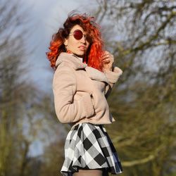 Portrait of young woman standing against trees