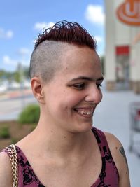 Close-up of happy young woman with hairstyle standing in city