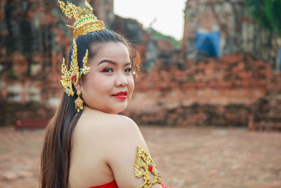 Asia woman wearing traditional thai dress, she is posting with ancient ruin temple background.