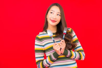 Portrait of a smiling young woman against red background