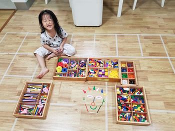 High angle portrait of girl with art and craft equipment sitting on floor at home
