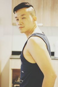 Side view portrait of man wearing tank top standing at home