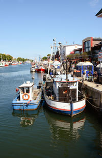 Fishing boats moored in canal against sky