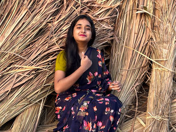 Portrait of young woman standing amidst hay