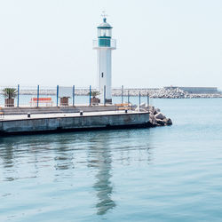 Lighthouse by sea against clear sky