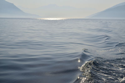 Sea surface with a land in a distance with a morning mist and sunlight twinkles and reflection