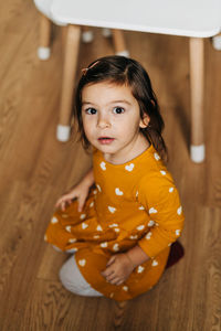 Portrait of cute girl sitting on floor at home