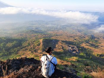 Young man looking at the view from the top of the mountain