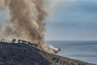 Airplane fighting forest fire against blue sky and sea