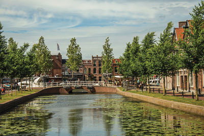 Bridge over river by buildings against sky in city