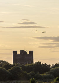 Airplanes flying over castle against sky