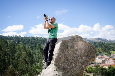 Low angle view of man standing on mountain against sky