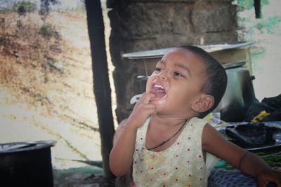 Girl with fingers in mouth standing at home