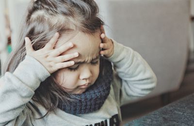 Cute girl with headache at home