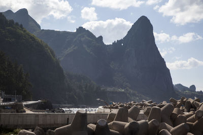 Tetrapods and rocky mountain against sky at ulleungdo