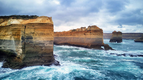 View of rocks in sea against cloudy sky