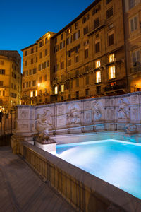 Reflection of building in swimming pool at night