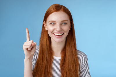 Happy woman gesturing against blue background