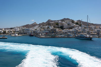 Scenic view of sea by buildings against clear blue sky