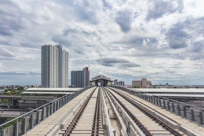 Railroad tracks in city against sky