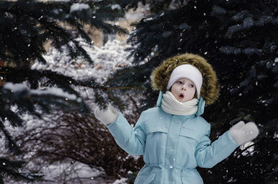 A little girl sings in the snow-covered trees.