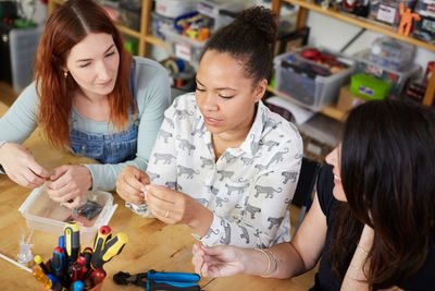 High angle view of female technicians sitting at table in workshop