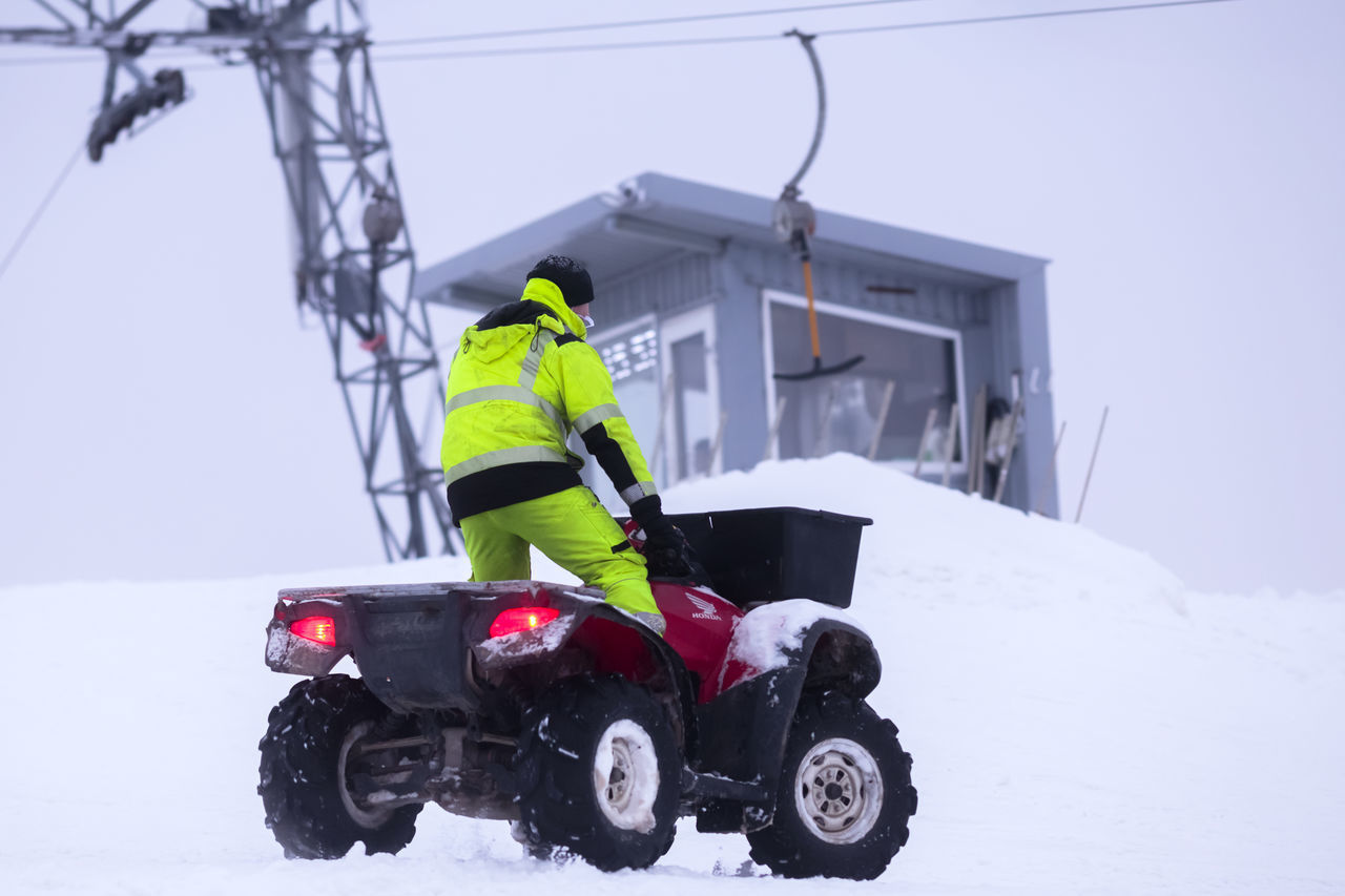 REAR VIEW OF MAN ON SNOW COVERED WITH CAR