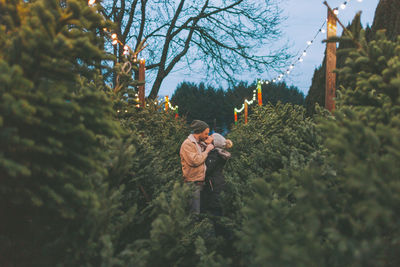 Couple amidst plants during sunset