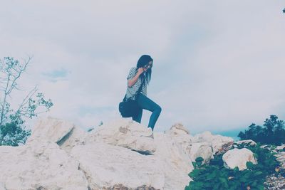 Woman standing on rock against sky