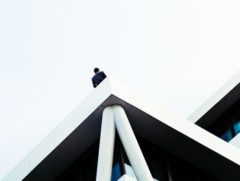 Low angle view of person on building against clear sky